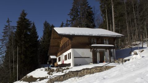 ein Holzhaus mit einem weißen Dach und einer Steinmauer 